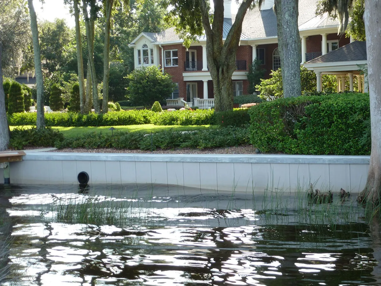 A low vinyl sheet-pile wall with a flat cap, seen from the water, with a lawn behind it.